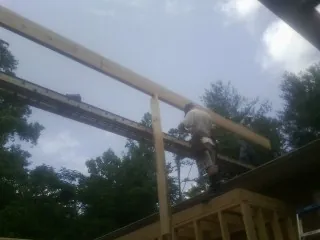Carpenter setting a ridge beam over a new addition frame — Ice Dam Removal by Roofing Brothers in Casnovia