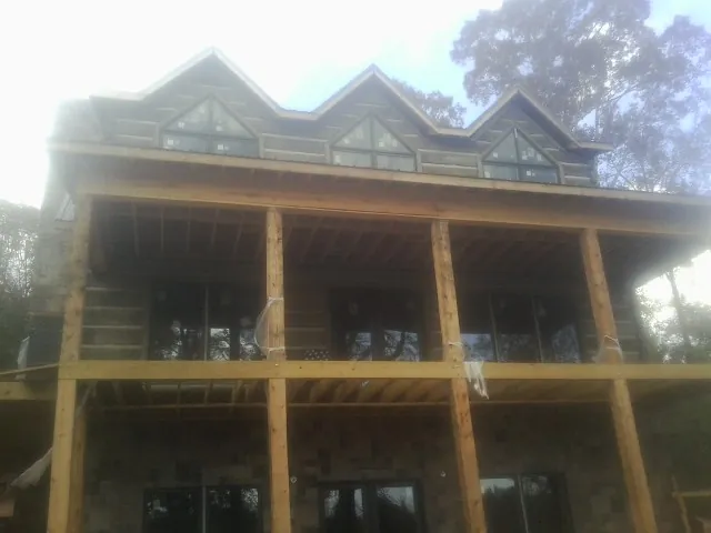 Dormers and porch framing on a large log home under construction — Roof Coating work by our crew in Casnovia