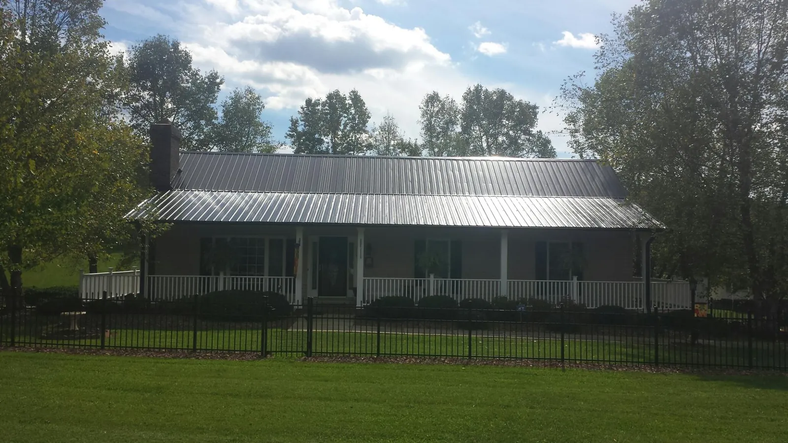 Gray metal roof on a brick ranch with a full width front porch — Gutter Guard Installation work by our crew in Casnovia