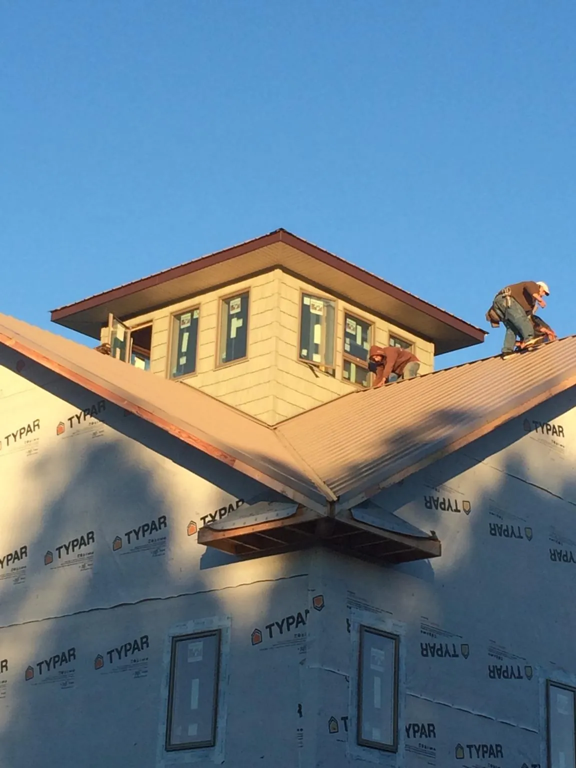 Roofers working around a rooftop cupola on a new metal roof at sunset — Roof Waterproofing in Casnovia by Roofing Brothers